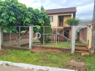 Vista externa de uma residência com cerca e vegetação no Brasil.