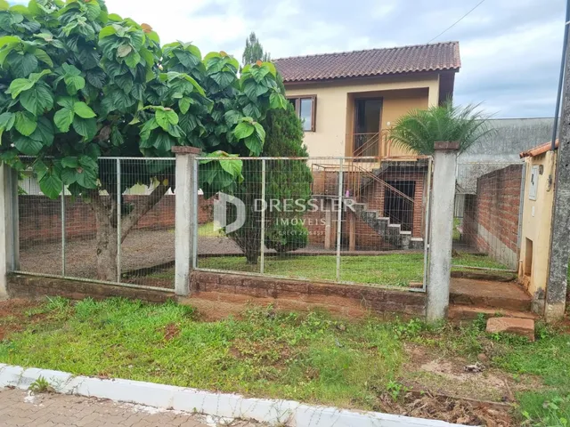 Vista externa de uma residência com cerca e vegetação no Brasil.