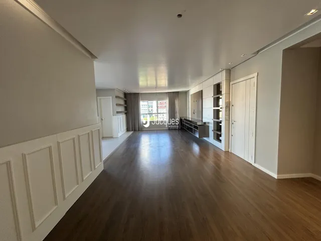 Hall de entrada com piso de madeira e painéis brancos.