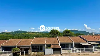 Vista externa de uma fileira de casas com telhados de telha vermelha sob um céu azul.