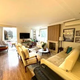 Foto interna de uma sala com piso de madeira e móveis.