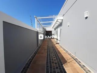 Vista lateral de um corredor longo com estrutura de cobertura de vidro em um edifício residencial em Lajeado, Brasil.