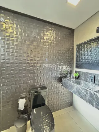 Banheiro com revestimento de azulejos geométricos escuros.