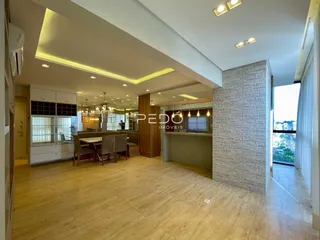 Sala de estar com piso de madeira clara e teto com iluminação embutida.