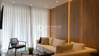 Sala de estar com grandes janelas cobertas por cortinas brancas.