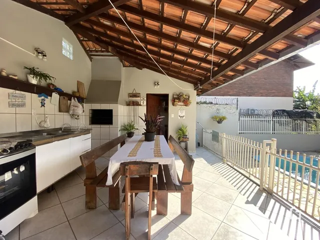 Vista interna de uma área de cozinha com teto de madeira e vista para o quintal.