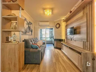 Sala de estar com piso de madeira e lareira em um apartamento.