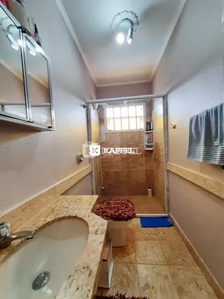 Foto do banheiro mostrando a bancada de mármore e a entrada para o box.