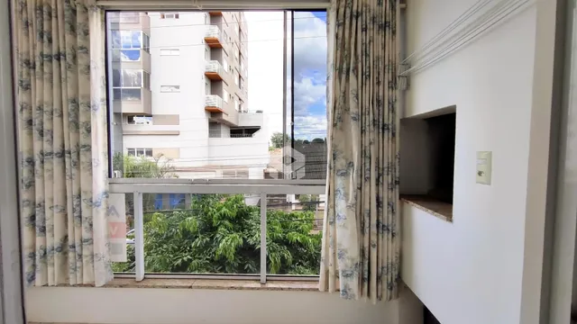 Vista externa de árvores verdes através da janela de uma propriedade em Lajeado.