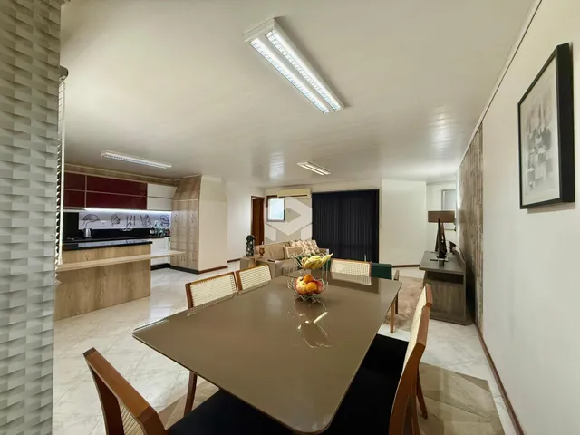 Vista de uma sala de jantar com mesa de madeira e cozinha em um imóvel.