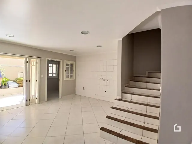 Um corredor interno com piso de cerâmica e escadaria visível na propriedade.