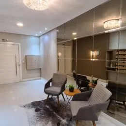 Foto interna de uma sala com paredes claras e iluminação brilhante.