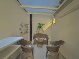 Sala de estar com sofás de vime e uma planta decorativa.