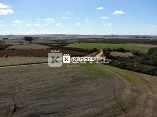 Vista aérea de uma área rural aberta com campos verdes e terra.