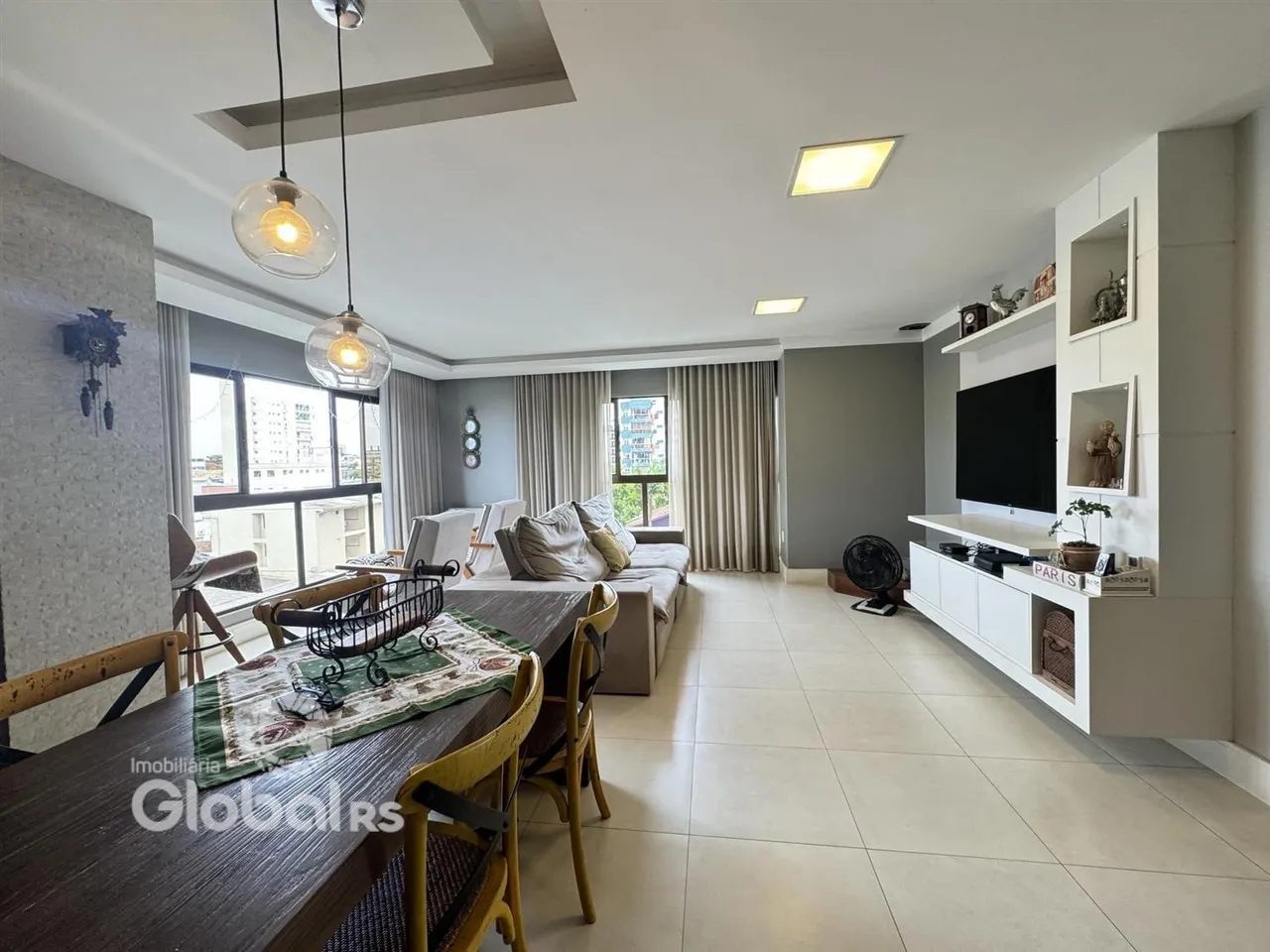 Sala de estar e jantar com grandes janelas em um apartamento.