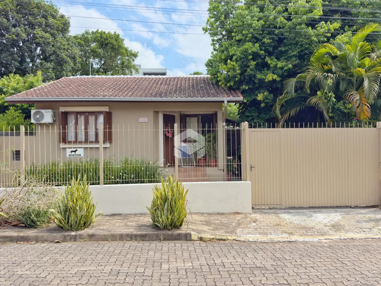 Fachada de uma casa em Lajeado, Brasil, com cerca e jardim na frente.