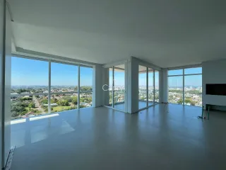 Uma sala ampla com grandes janelas oferece uma vista panorâmica da cidade.