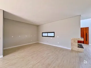 Ambiente interno de uma sala ampla com piso de madeira clara.