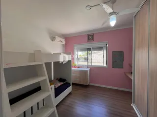 Um quarto com cama de beliche e estantes brancas em uma residência.