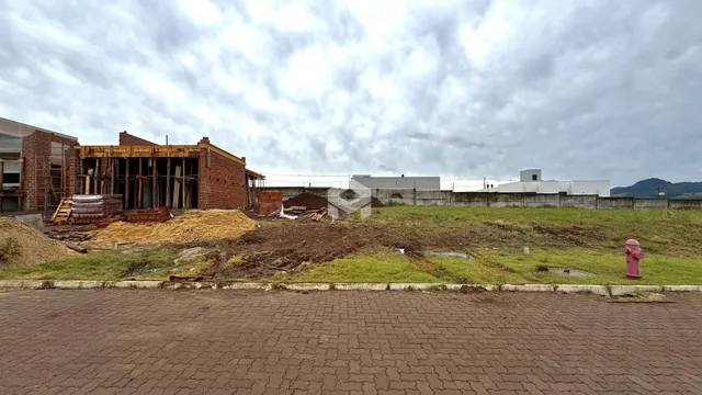 Vista externa de uma construção com paredes de tijolo expostas e terra em Lajeado, Brasil.