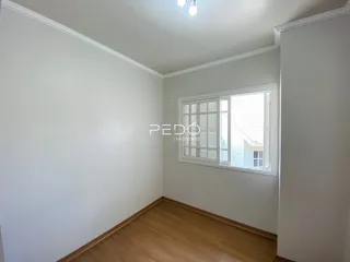 Interior de um cômodo com paredes brancas e piso de madeira clara.
