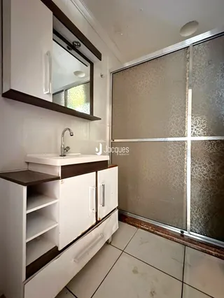 Armários brancos de cozinha com bancada e pia em um imóvel no Brasil.