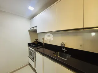 Foto de uma cozinha com armários brancos e bancada escura.