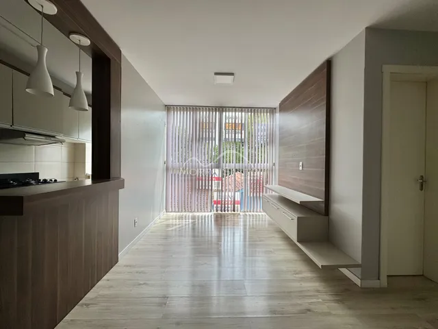 Ambiente interno com piso de madeira clara e área de cozinha moderna.