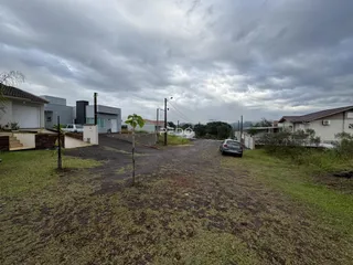 Vista externa de uma propriedade com gramado e área de terra no quintal.