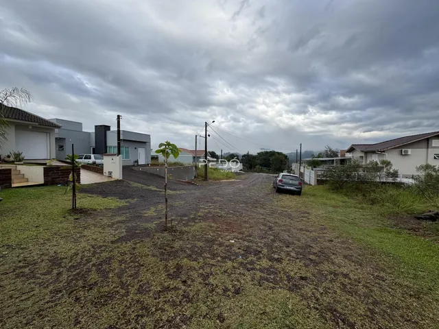 Vista externa de uma propriedade com gramado e área de terra no quintal.