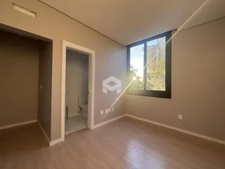 Interior de uma sala com piso de madeira e porta de acesso ao banheiro.