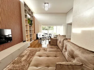 A sala de estar apresenta um sofá grande e piso de madeira.