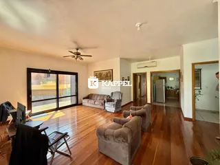 Sala de estar com piso de madeira e portas de vidro que dão acesso ao exterior.