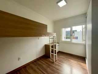 Ambiente interno de uma sala com piso de madeira e janela.