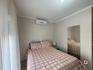 Quarto com cama de casal e janela em ambiente claro.