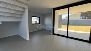 Sala de estar com piso claro e porta de vidro que dá acesso ao exterior.