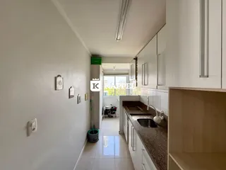 Corredor que leva à cozinha com paredes brancas e piso de cerâmica claro.
