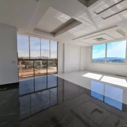Sala ampla com grandes janelas e teto branco.
