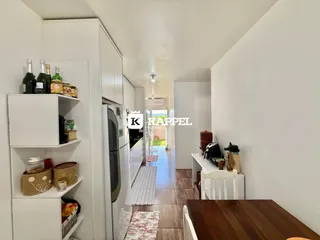 Foto de uma cozinha com armários brancos e um corredor iluminado.
