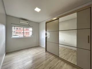 Ambiente interno de uma sala com piso de madeira clara e parede branca.