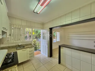 Foto de uma cozinha com armários brancos e piso de cerâmica clara.