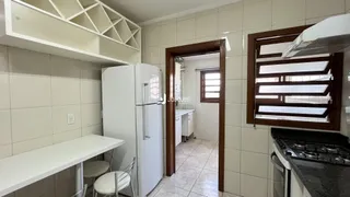 Foto interna de uma cozinha com armários brancos e revestimento cerâmico.