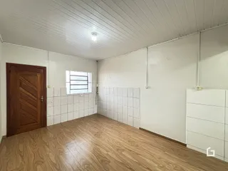 Ambiente interno de uma sala com piso de madeira e paredes brancas.
