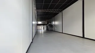 Corredor longo com paredes brancas e piso claro.