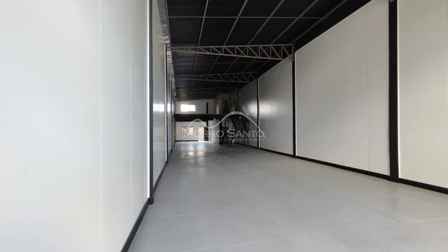 Corredor longo com paredes brancas e piso claro.