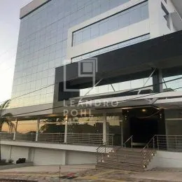 Fachada moderna de um edifício com grandes painéis de vidro e estrutura escura.