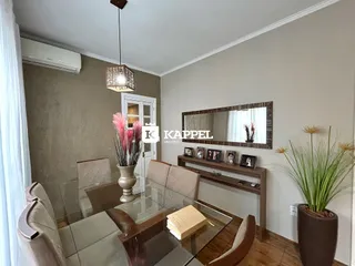 Uma sala de jantar com mesa de vidro e cadeiras em um imóvel em Lajeado.