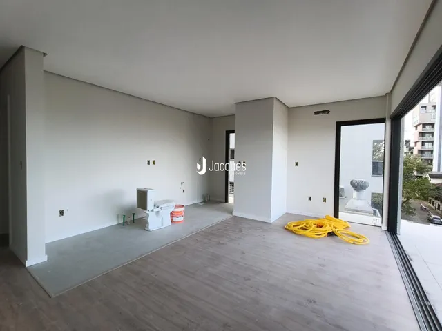 Ambiente interno de uma sala de estar moderna com paredes brancas e piso de madeira clara.