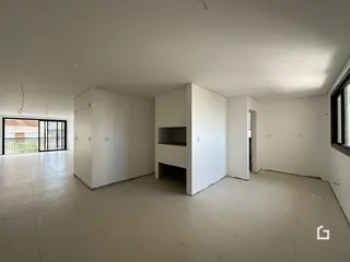 Interior de uma sala ampla com piso de cerâmica e paredes brancas.