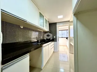Vista da cozinha com armários brancos e revestimento preto na Lajeado.